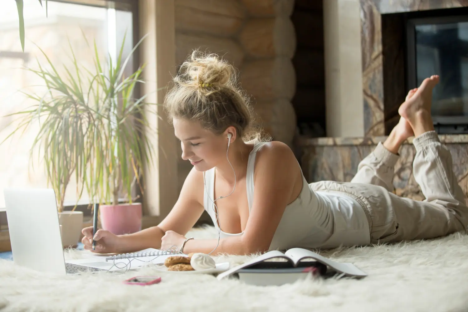 Woman working on laptop at home, enjoying a relaxed moment with a cozy background.