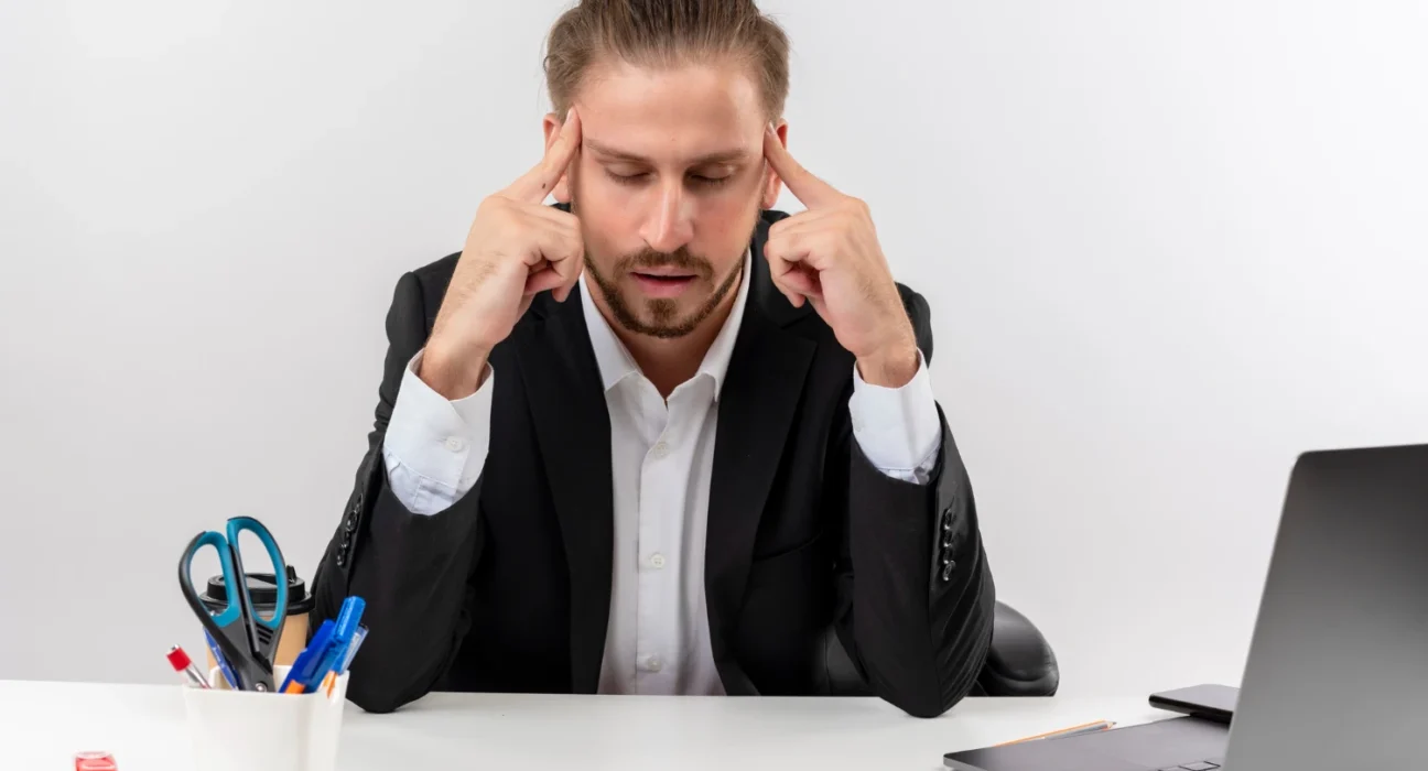 Stressful businessman with head in hands, overwhelmed by small problems turning into big issues.