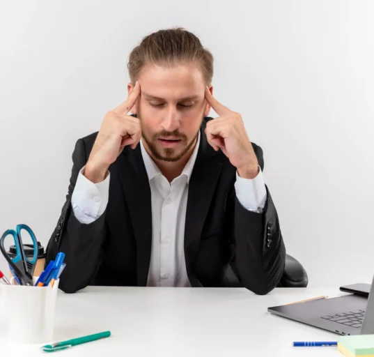 Stressful businessman with head in hands, overwhelmed by small problems turning into big issues.