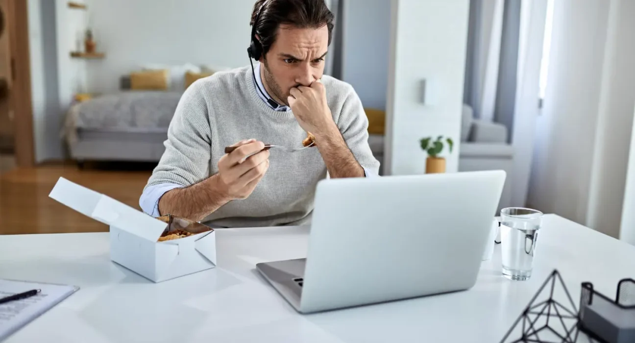 Man struggling with multiple tasks on his laptop, showing stress and frustration.
