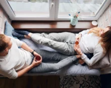Couple lying on a couch, feeling lonely despite being together.