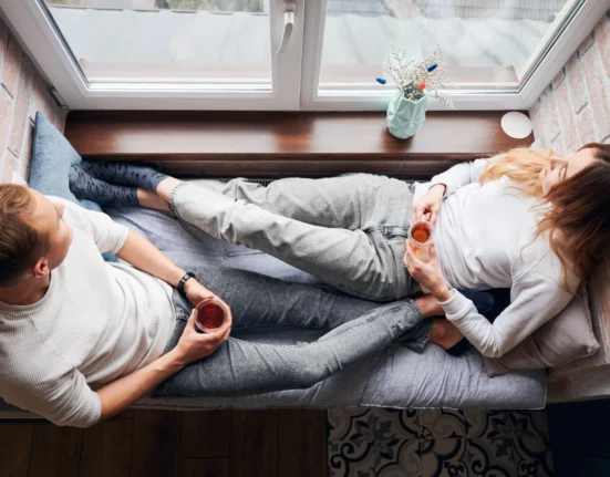 Couple lying on a couch, feeling lonely despite being together.