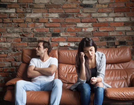 Couple sitting apart on a sofa, showing emotional distance after a breakup.