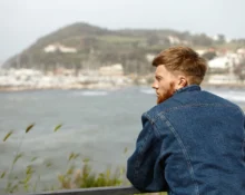 Young man contemplating by the water, symbolizing resilience after loss and discovering new opportun.
